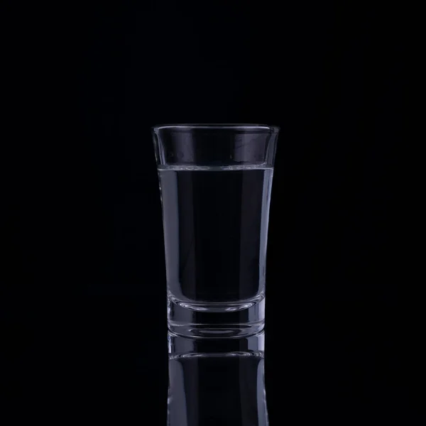 shot glasses with vodka on a black background.