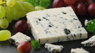 Taş tahtada yeşil ve kırmızı üzümlü Gorgonzola peyniri. Döndürme videosu