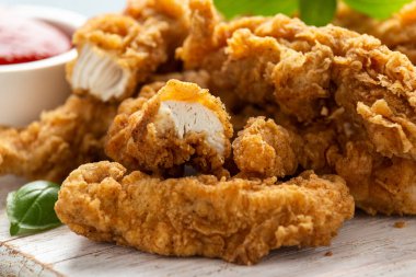 Beyaz tahta üzerinde ketçaplı kızarmış tavuk şeritleri. Fast Food