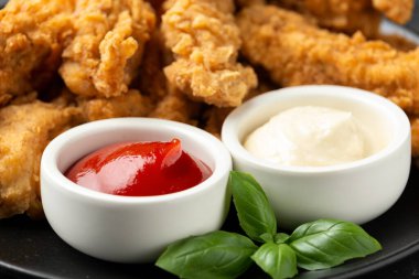 Kızarmış tavuk şeritleri ve siyah tabakta ketçap ve mayonez. Fast Food
