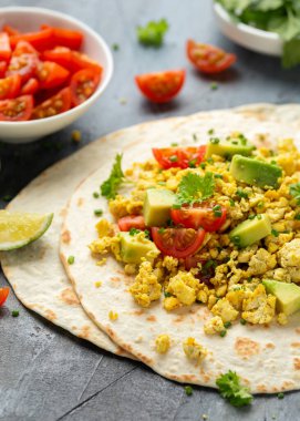 Avokado, domates ve yeşil bitkilerle çırpılmış tofu tacoları. Sağlıklı Vegan Kahvaltısı.