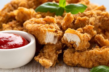 Beyaz tahta üzerinde ketçaplı kızarmış tavuk şeritleri. Fast Food