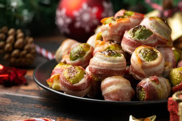 Christmas Streaky bacon wrapped Brussel sprouts with decoration, gifts, green tree branch on wooden rustic table — Stock Photo, Image