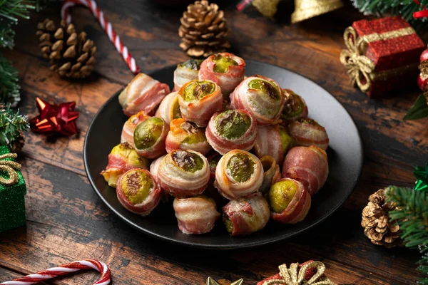 Christmas Streaky bacon wrapped Brussel sprouts with decoration, gifts, green tree branch on wooden rustic table — Stock Photo, Image