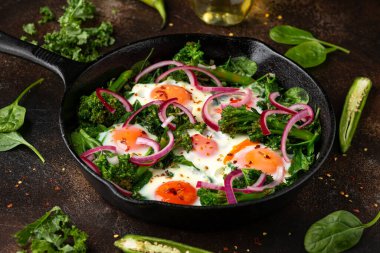 Sarı yumurtalı yeşil shakshuka, lahana, ıspanak ve soğan turşusu ve biberli brokoli.