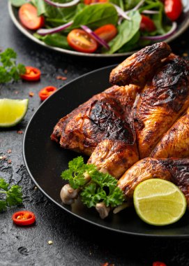 Tabaka usulü kızarmış tavuk, siyah tabakta salata, mısır ve limon..