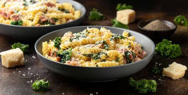 Fusilli pasta with bacon, kale and parmesan cheese. Healthy food