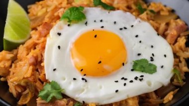 Kızarmış yumurta ve pastırmalı kimchi pilavı. Kore yemeği. Döndürme videosu