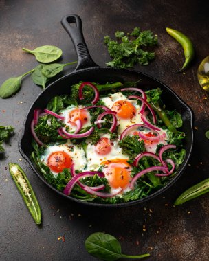 Sarı yumurtalı yeşil shakshuka, lahana, ıspanak ve soğan turşusu ve biberli brokoli.