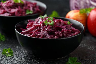 Elmalı haşlanmış kırmızı lahana ve siyah kasede kırmızı frenk üzümü.