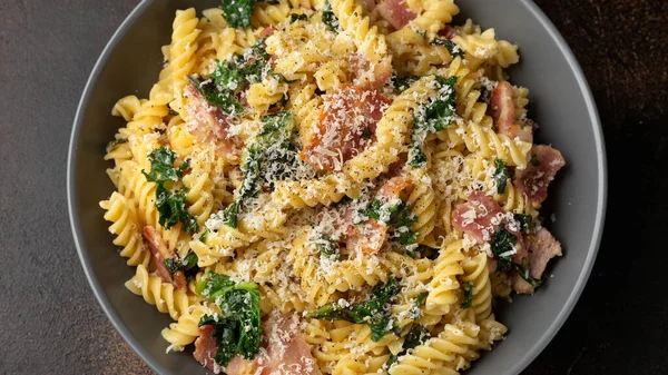 Fusilli pasta with bacon, kale and parmesan cheese. Healthy food