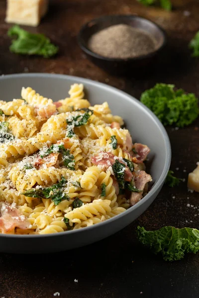 Fusilli pasta with bacon, kale and parmesan cheese. Healthy food