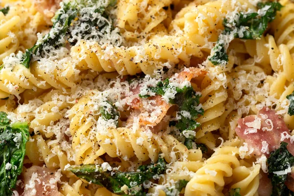 Fusilli pasta with bacon, kale and parmesan cheese. Healthy food.