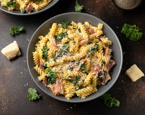 Fusilli pasta with bacon, kale and parmesan cheese. Healthy food.