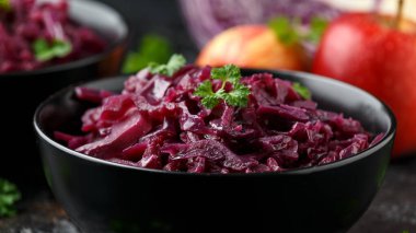 Elmalı haşlanmış kırmızı lahana ve siyah kasede kırmızı frenk üzümü..