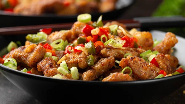 소금 과 후추 돼지고기를 검은 그릇에 허브와 함께 볶는다. 아시아 음식 — 스톡 사진