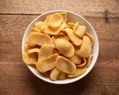 Tahta masada beyaz kasede gevrek karides krakerleri.