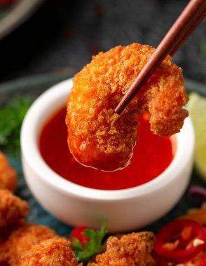 Ekmek kırıntıları içinde gevrek karidesler. Lahana, havuç salatası, soya ve acı biber sosuyla servis edilir.