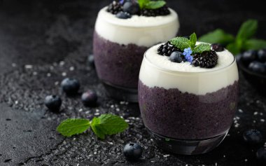 Taze böğürtlenli bardakta sağlıklı vanilyalı yaban mersini pudingi.