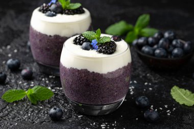 Taze böğürtlenli bardakta sağlıklı vanilyalı yaban mersini pudingi.