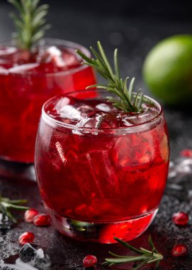 Limonlu, biberiyeli ve sade siyah masada buzlu nar cini kokteyli.