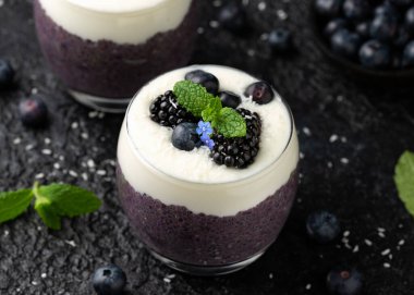 Taze böğürtlenli bardakta sağlıklı vanilyalı yaban mersini pudingi..