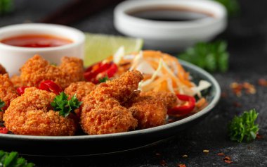 Ekmek kırıntıları içinde gevrek karidesler. Lahana, havuç salatası, soya ve acı biber sosuyla servis edilir..