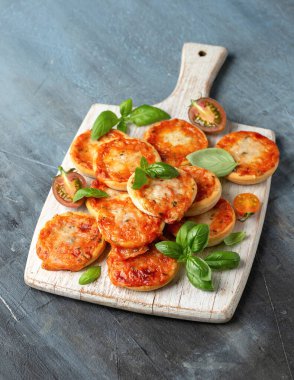 Domatesli mini pizzalar ve beyaz tahta üzerinde mozzarella peyniri..