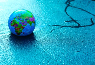 Dünya gezegeninin bir maket küresi mavi renkli su damlalarının arka planına karşı.