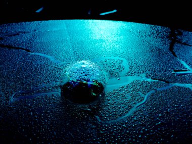 Mavi renkli, su damlalarının arka planına karşı şeffaf bir küre