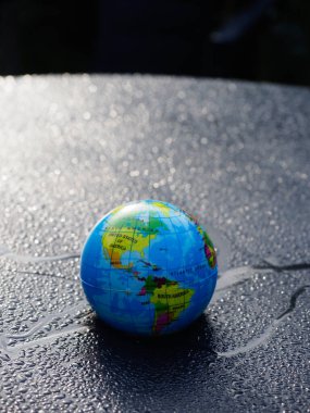 Dünya gezegeninin bir maket küresi mavi renkli su damlalarının arka planına karşı.