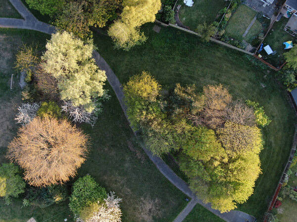 Drones eye view of a small park and childrens play area surrounded by attractive trees and houses