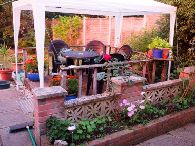 Plastik bahçe sandalyeleri ve masa beyaz plastik bir çardağın altında küçük tahta bir parça üzerinde