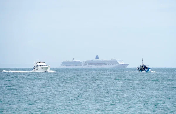 Dois grandes navios de cruzeiro ancorados no mar com um cruzador a motor e um pequeno barco de pesca em primeiro plano — Fotografia de Stock