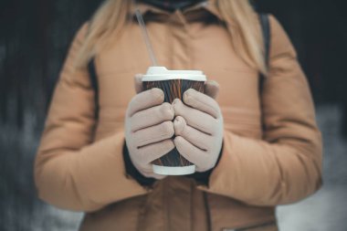 Eldivenli kızın elleri bir fincan sıcak kakao ya da kahve tutuyor, fotokopi çekilen tonlu fotoğraf.
