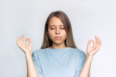 Beyaz arka planda gözleri kapalı, aklı başında, genç sarışın kadın ellerini Mudra jestine sokuyor. Huzurlu kız yoga işaretinde parmaklarını tutarak meditasyon yapıyor.