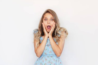 Mavi elbiseli, dalgalı saçlı, beyaz bir arka planda indirimli satış ve indirim haberleri karşısında şaşıran, güzel, beyaz tenli, güzel, beyaz bir kadın.