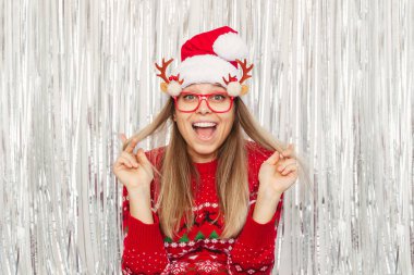 Noel Baba şapkası ve komik gözlüklerle poz veren neşeli kadın.