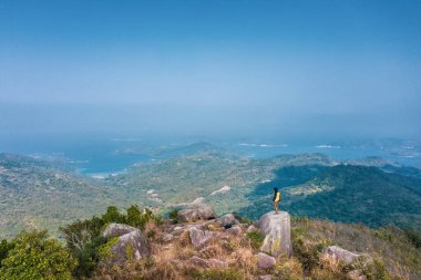 Kayanın üzerinde duran adam, Sonbaharda Sai Kung, Hong Kong 'da yürüyüş yapıyor.