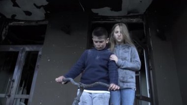 Bir oğlan ve bir kız roketler tarafından vurulduktan sonra evlerinde duruyorlar, küçük bir oğlan ve küçük bir kız savaşın kurbanları.