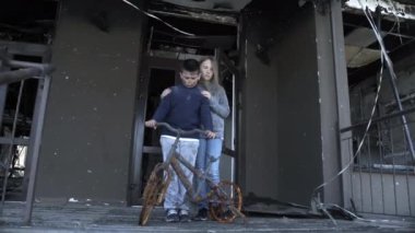 Bir oğlan ve bir kız roketler tarafından vurulduktan sonra evlerinde duruyorlar, küçük bir oğlan ve küçük bir kız savaşın kurbanları.