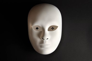 Kumarbaz, beyaz maske ve siyah arka planda iskambil kartları