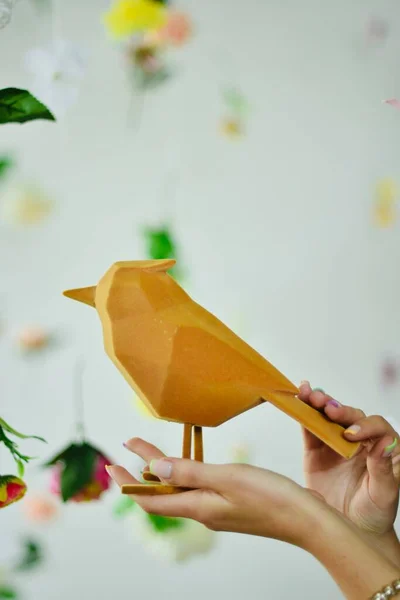 Bird for decoration in the hands of a young girl, on a floral background. copy space