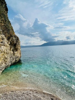  Arnavutluk 'taki Rocky plajı ve İyon Denizi' nin kristal turkuaz suyu. Uzayı kopyala Şeffaf su ve dalgalar. Yaz tatili kavramı.