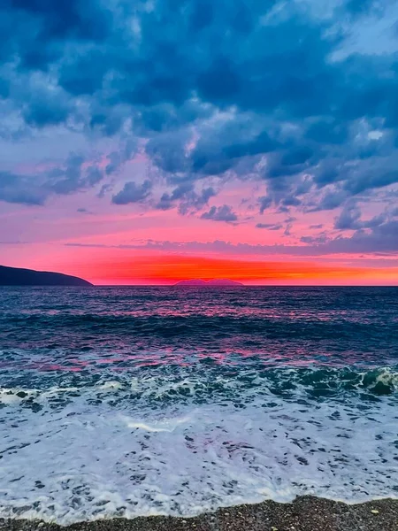 Vlore Arnavutluk 'taki İoninan Denizi üzerinde günbatımı manzarası. Sakin dalgalarla dalgalanan güzel bir su. Dikey fotoğraf. Boşluğu kopyala