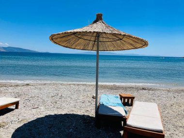 Mavi gökyüzünde saman şemsiyeleri ve deniz arka planında fotokopi alanı olan deniz şemsiyeleri. Seyahat, turizm, tatil beldesi, yaz tatili konsepti. Yatay fotoğraf.