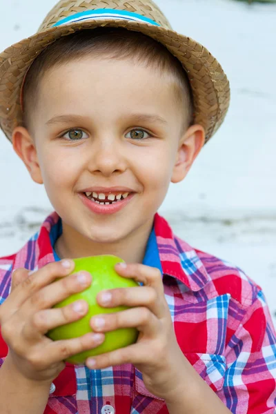 Felice ragazzo in una camicia colorata mentre mangia mela verde — Foto Stock