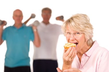 Mature lady eating cake at the gym clipart