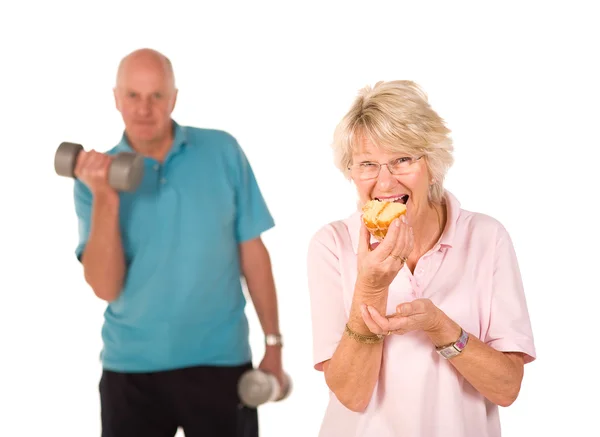 Mature lady eating cake at the gym — Stock Photo, Image