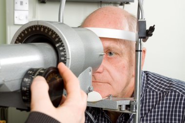 Older man having eye examination clipart